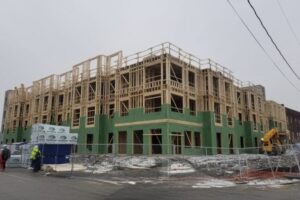 Jackson Ward Construction Progress: Framing and Sheathing Construction site of the Jackson Ward project showing the multi-story wood-frame structure with green moisture-resistant sheathing partially installed.