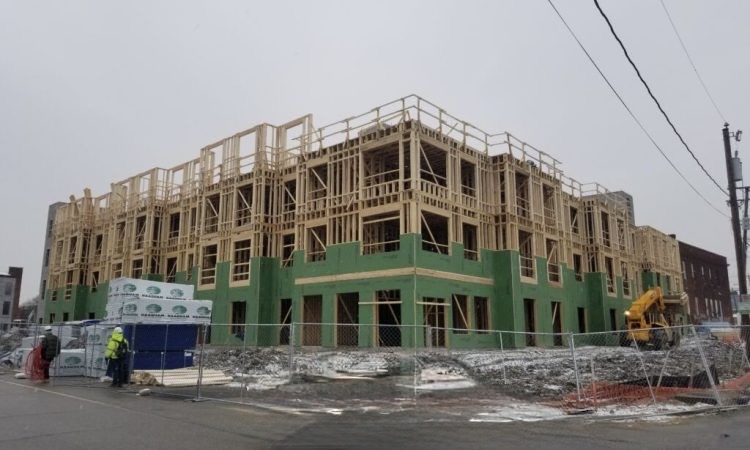 Construction site of the Jackson Ward project showing the multi-story wood-frame structure with green moisture-resistant sheathing partially installed.