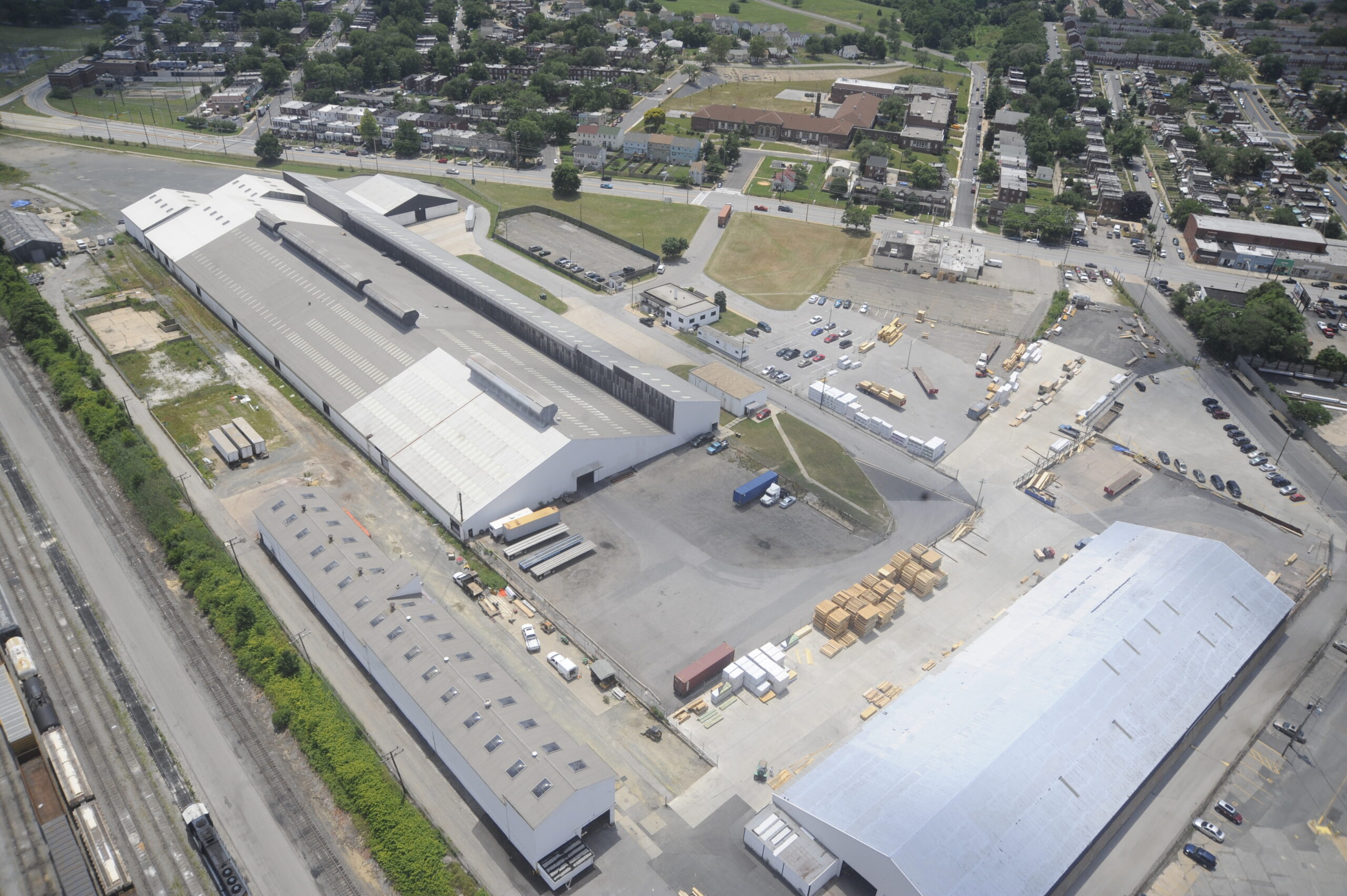 Aerial view of the Modu Tech industrial facility, showcasing large warehouse buildings, outdoor material storage yards, and rail access.